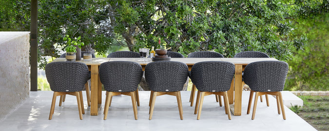 Conjunto de comedor al aire libre moderno con sillas negras y una mesa de madera.