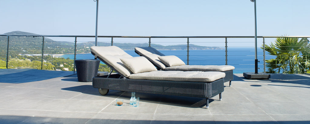 Dos sillones modernos grises y negros en una terraza con vistas al océano.