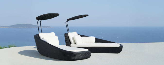 Sillas de lounge negras modernas con cojines blancos con vistas al mar.