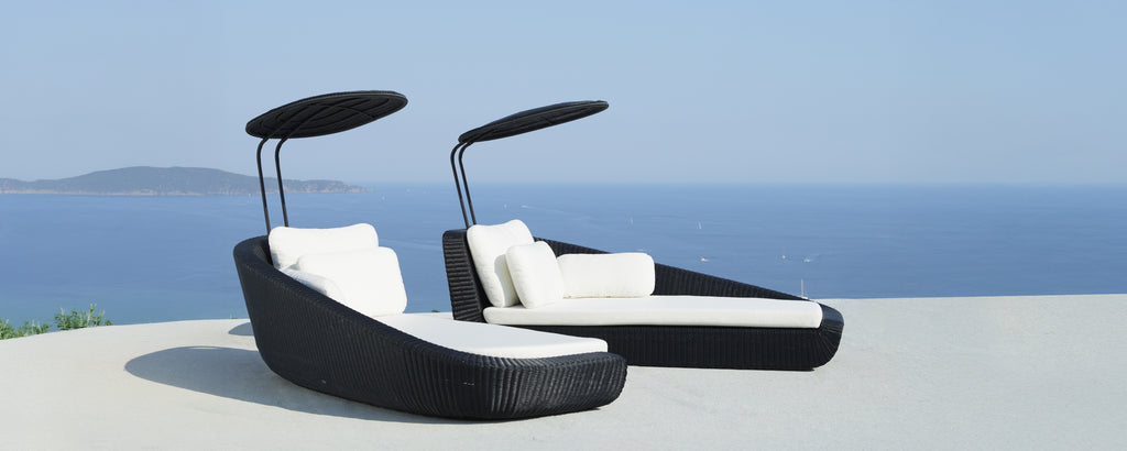 Sillas de lounge negras modernas con cojines blancos con vistas al mar.