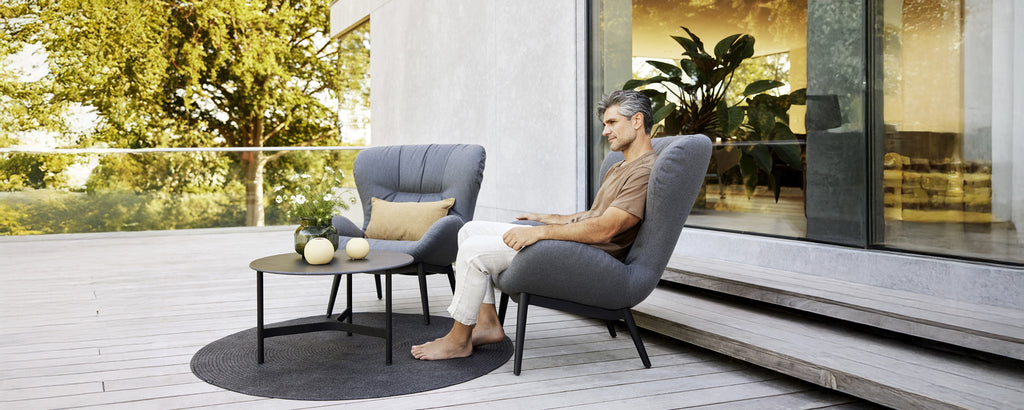 Zona de lounge moderna con sillones grises, una mesa negra y una alfombra redonda.