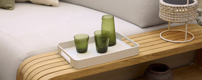 Configuración moderna de salón con cristalería verde en una bandeja blanca.