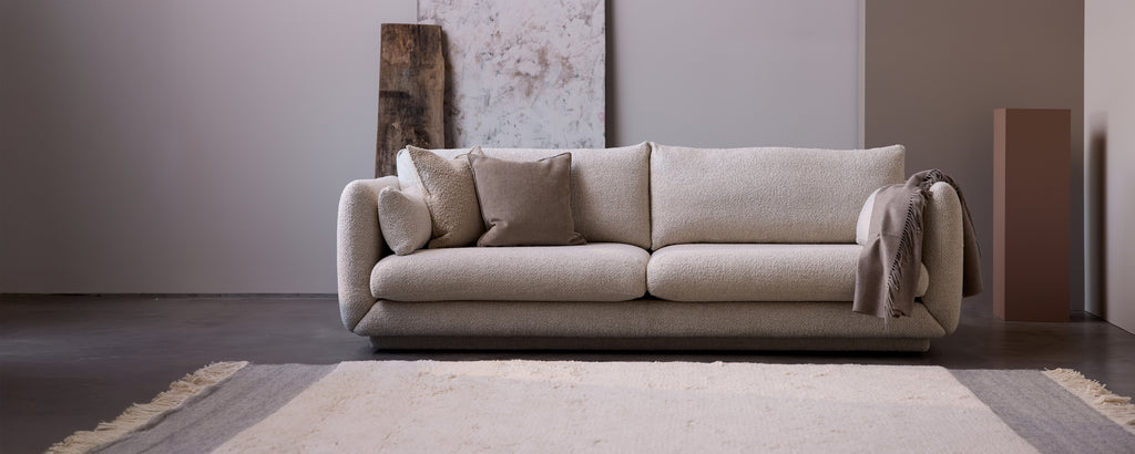 Sofá beige con cojines grises en un entorno de salón moderno.