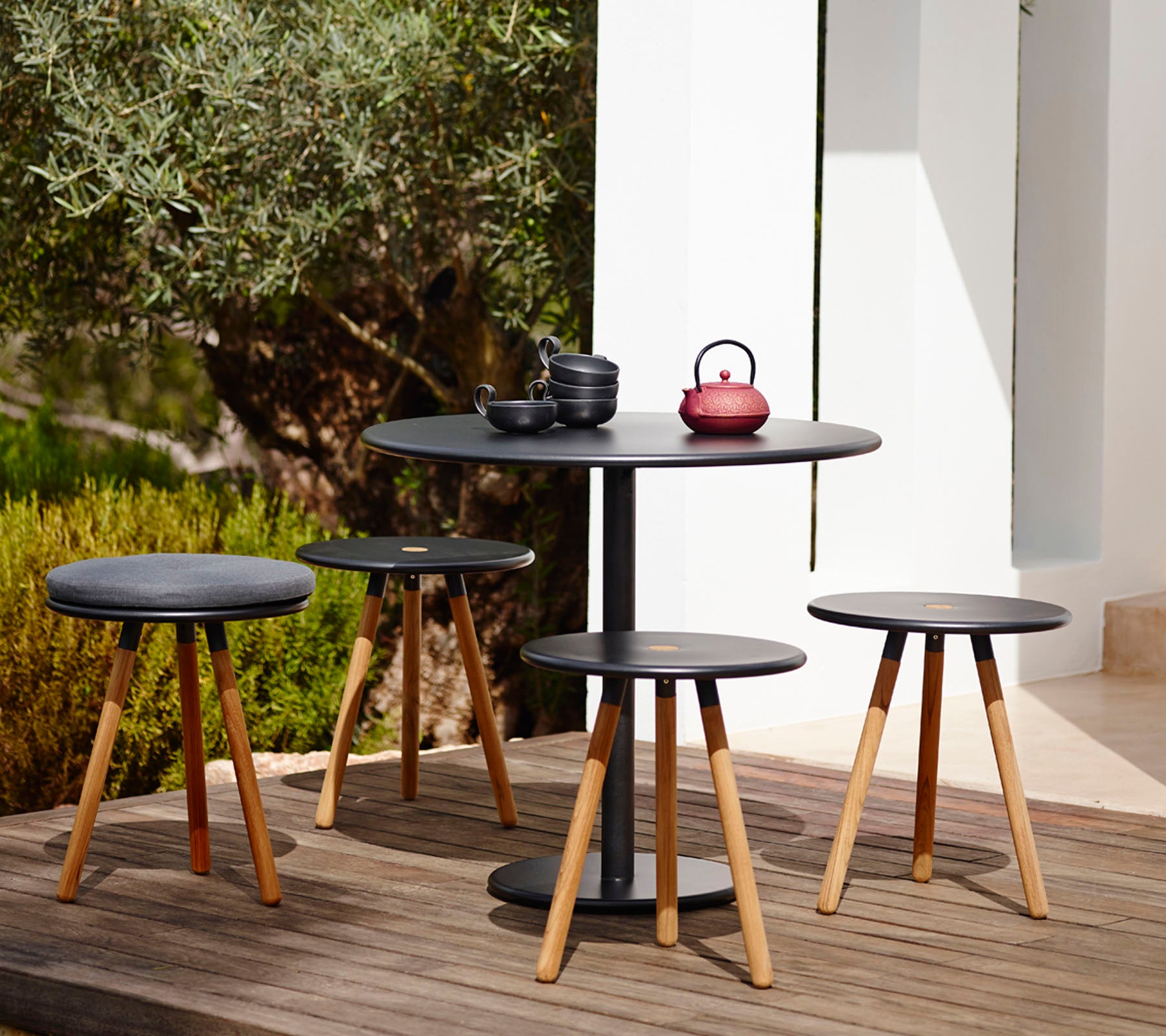 Conjunto de mesa y taburetes negros modernos en un entorno de jardín al aire libre.