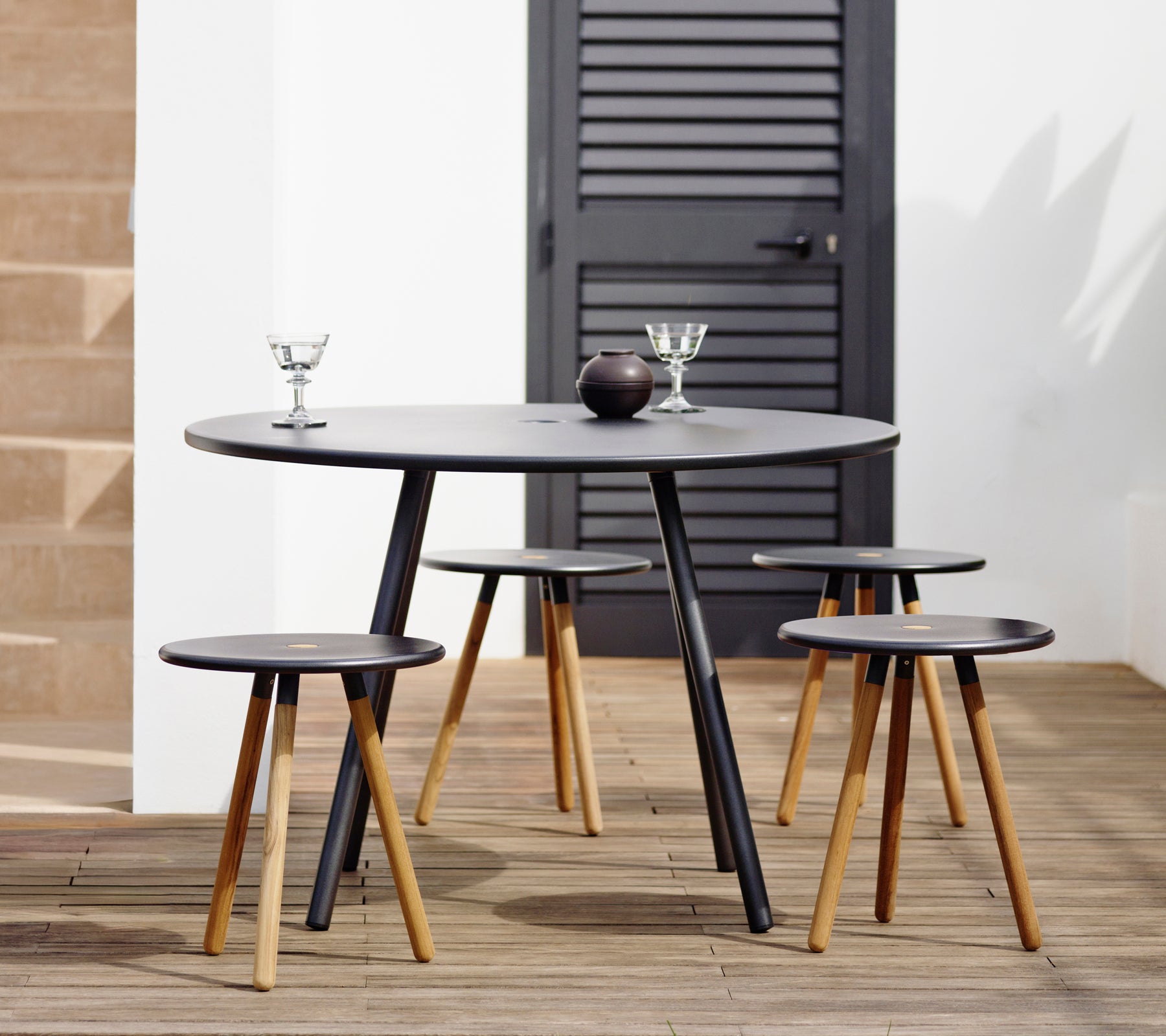 Mesa negra moderna con taburetes a juego en un entorno de salón elegante.
