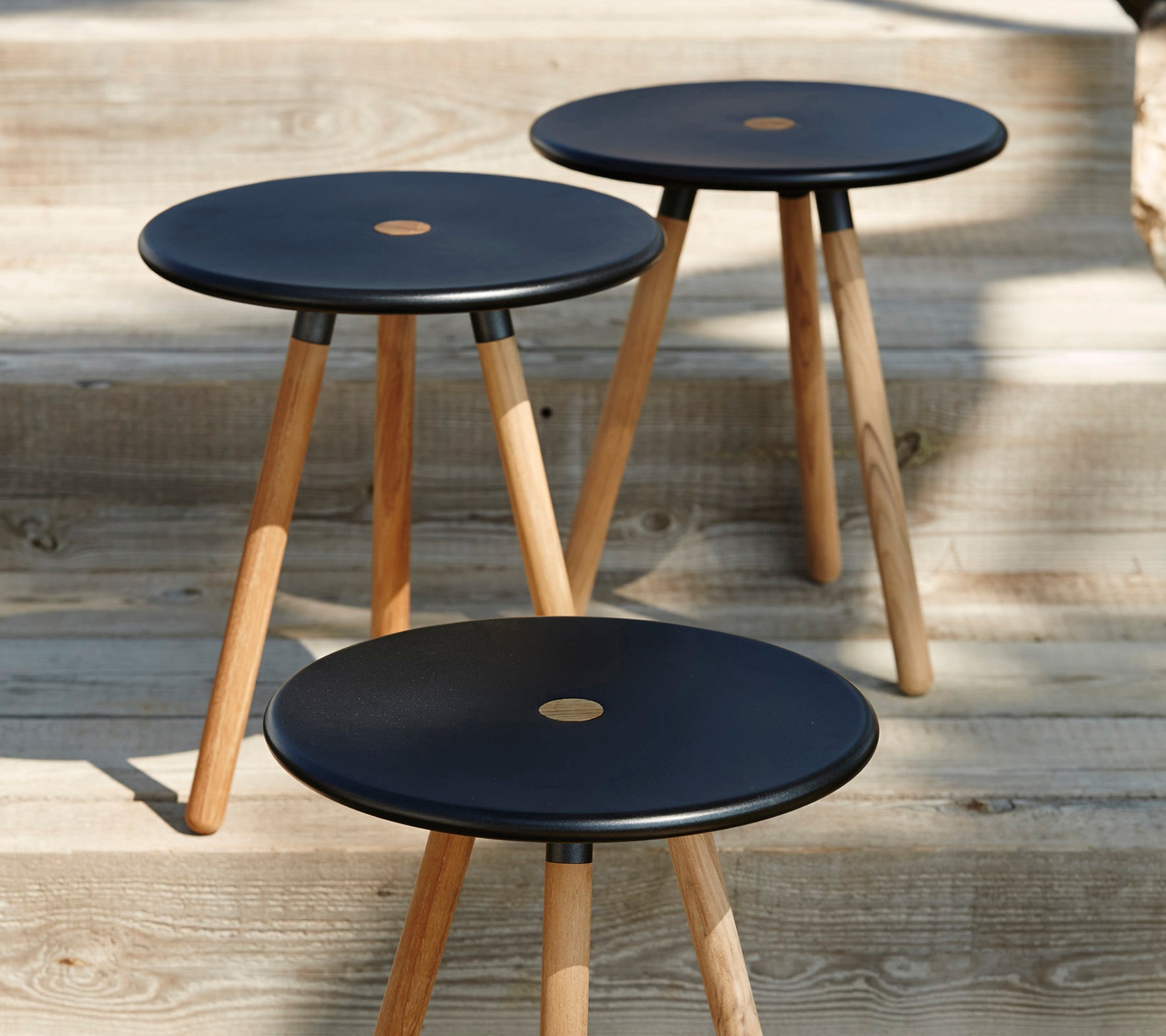 Tres taburetes negros modernos con patas de madera sobre una superficie de madera.