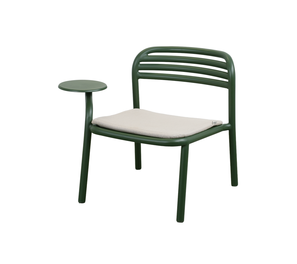Silla verde oscuro con un cojín de arena y mesa auxiliar.