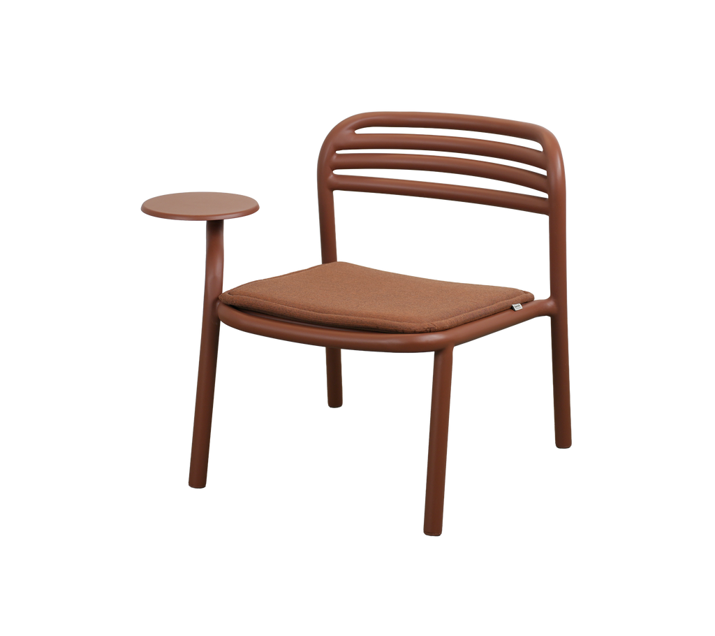 Silla moderna en rojo desierto con una pequeña mesa auxiliar.