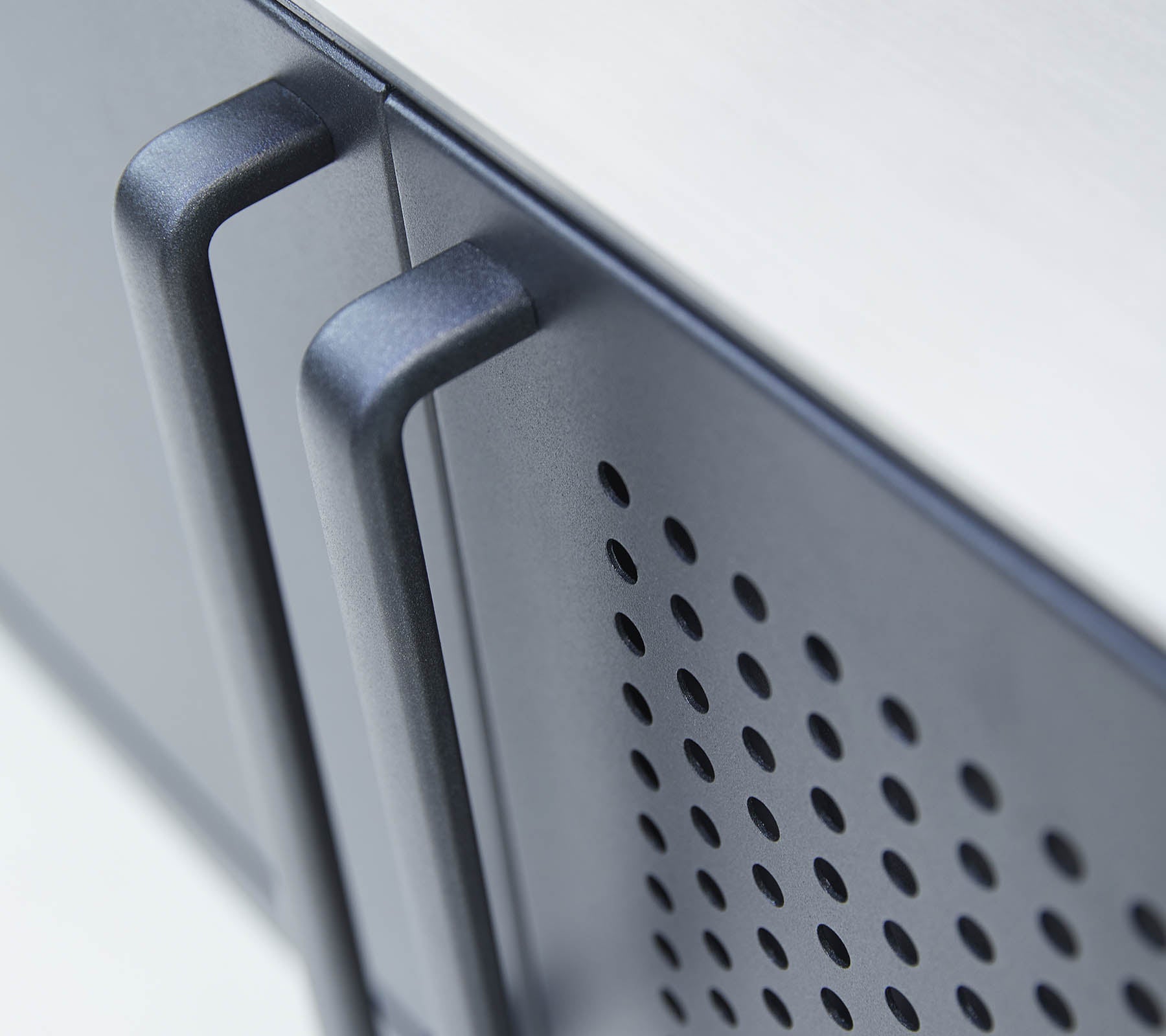 Vista en primer plano de un electrodoméstico elegante con dos asas y un patrón perforado en la superficie, enfatizando las características de diseño moderno.