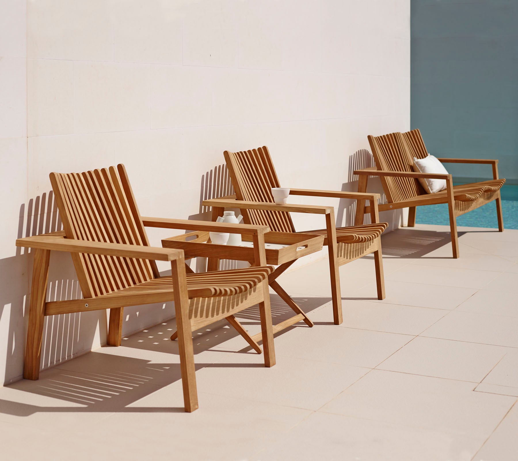 Tres sillones de madera con diseños de tablones dispuestos en fila, con un estilo simple y elegante adecuado para la relajación.