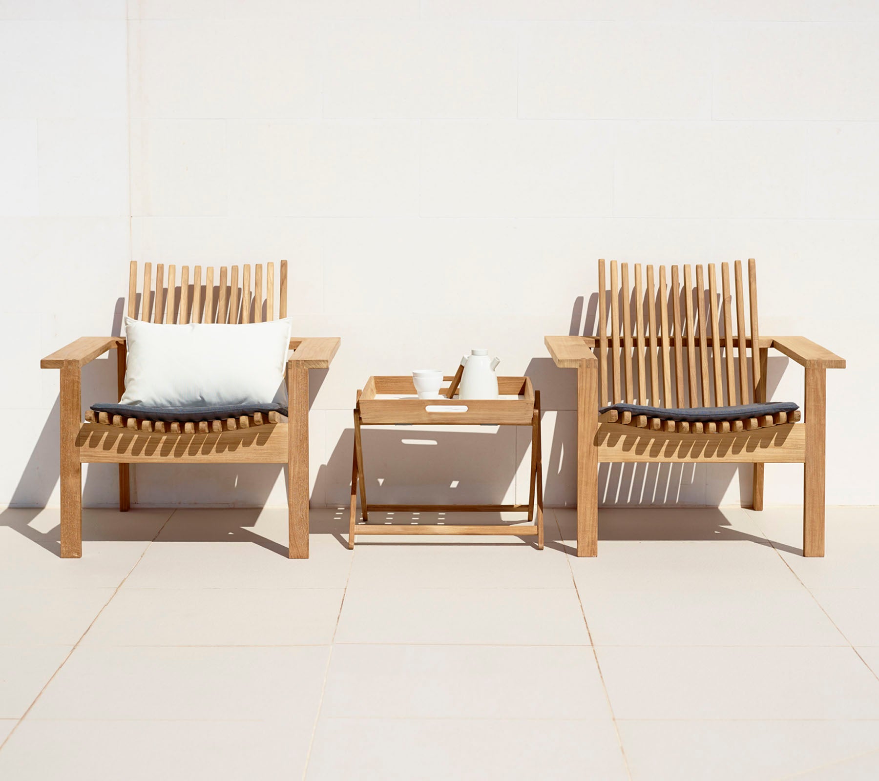 Dos sillas de madera elegantes con cojines y una pequeña mesa auxiliar, creando un área de estar acogedora.