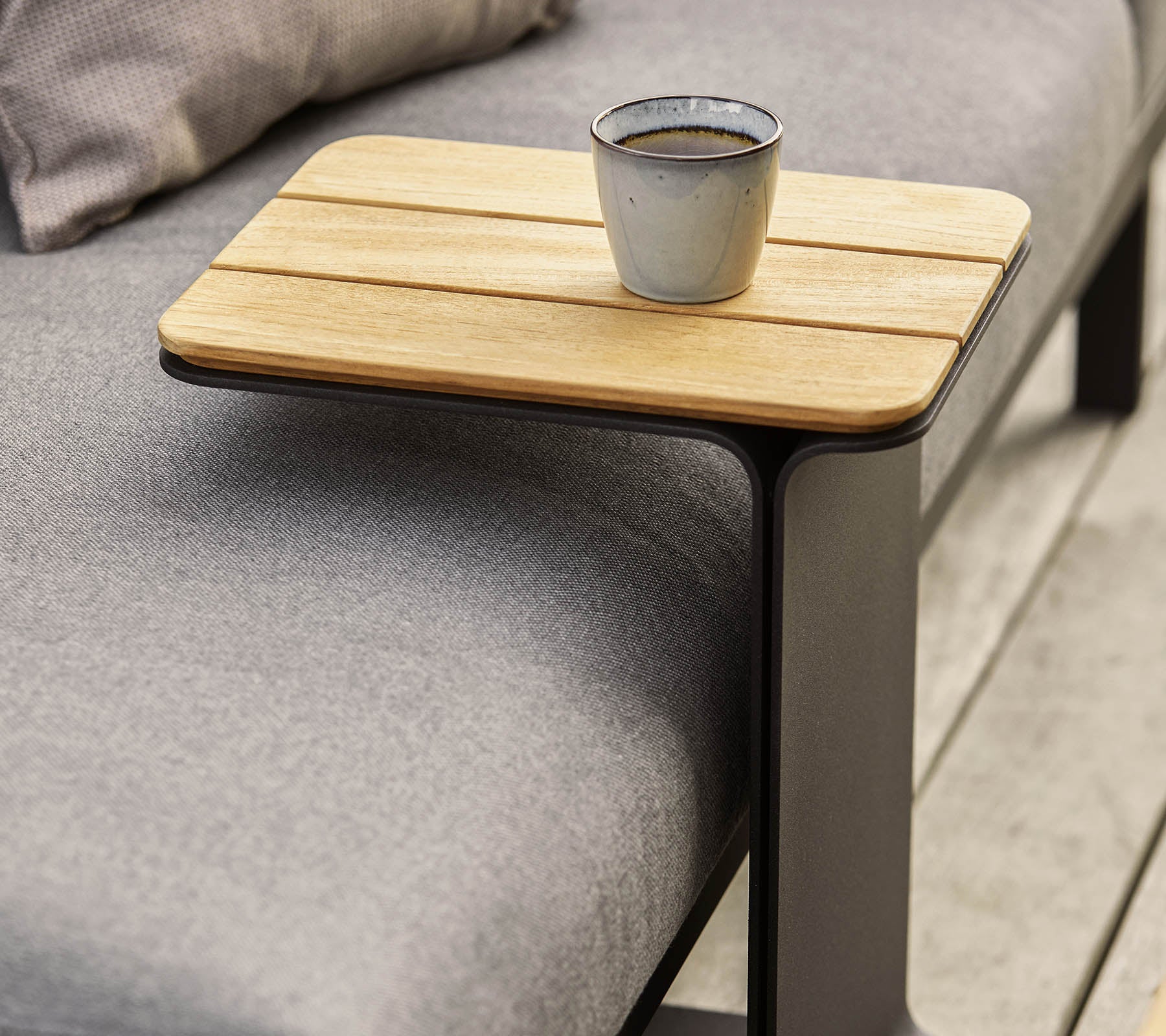 Una mesa auxiliar elegante con una superficie de madera y un marco de metal moderno, con una pequeña taza colocada sobre ella.