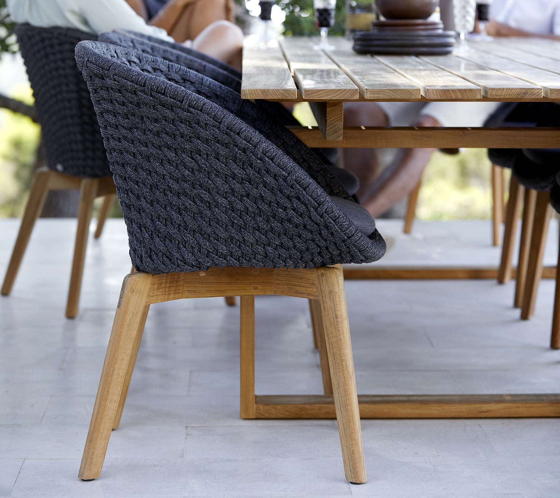 Silla tejida elegante con una base de madera, ubicada al lado de una mesa, que muestra un diseño moderno perfecto para espacios de reunión.