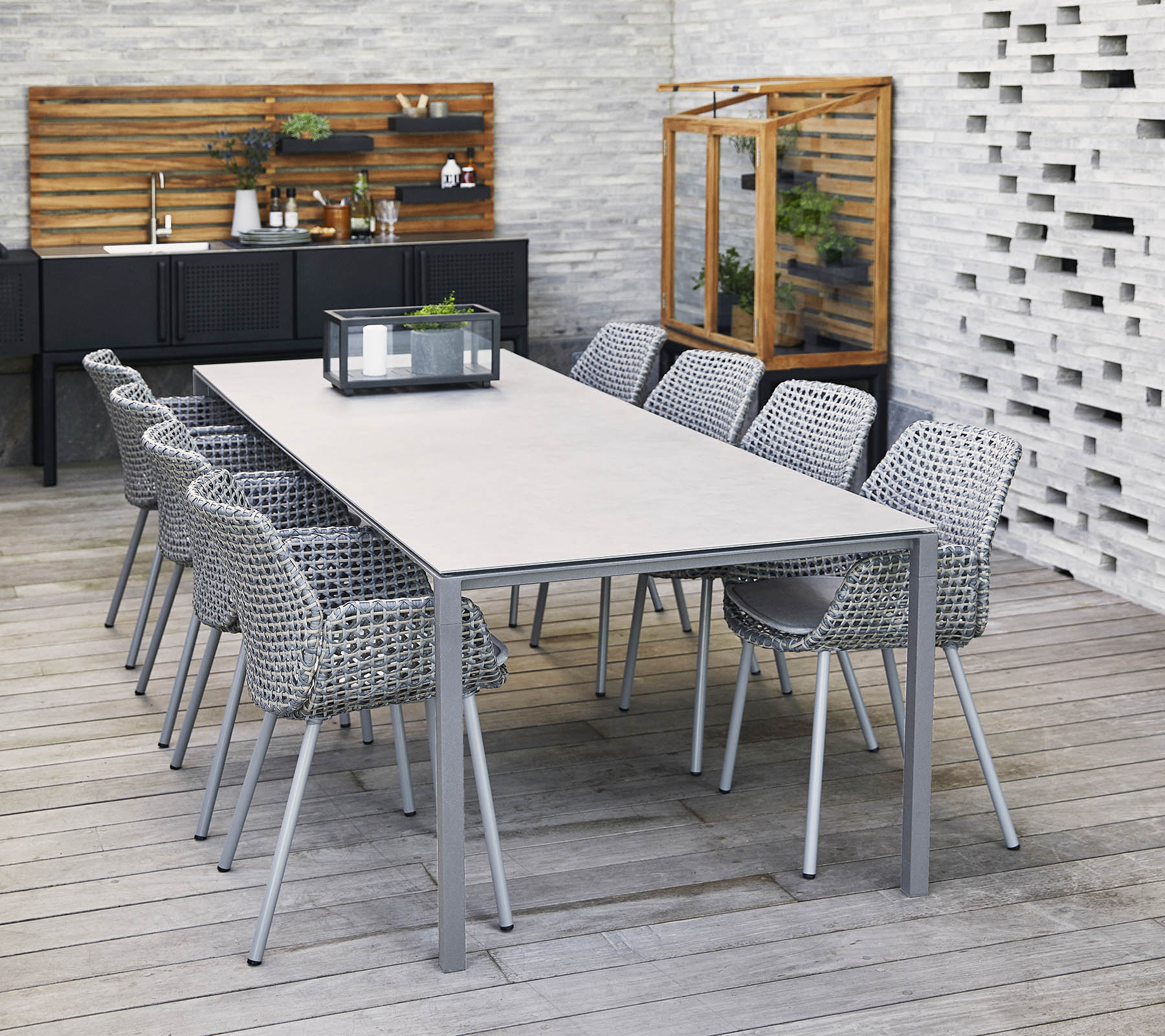 Una mesa larga y elegante rodeada de sillas tejidas, con un centro de mesa y elementos decorativos en un entorno contemporáneo.