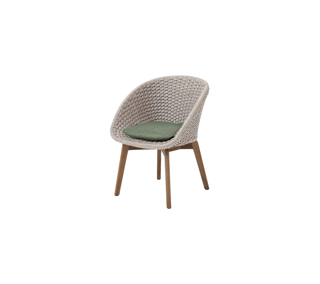 Una silla moderna de arena/teca con un cojín verde oscuro.