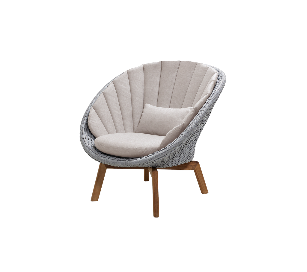 Silla moderna gris claro con cojín de color arena en un entorno de lounge.