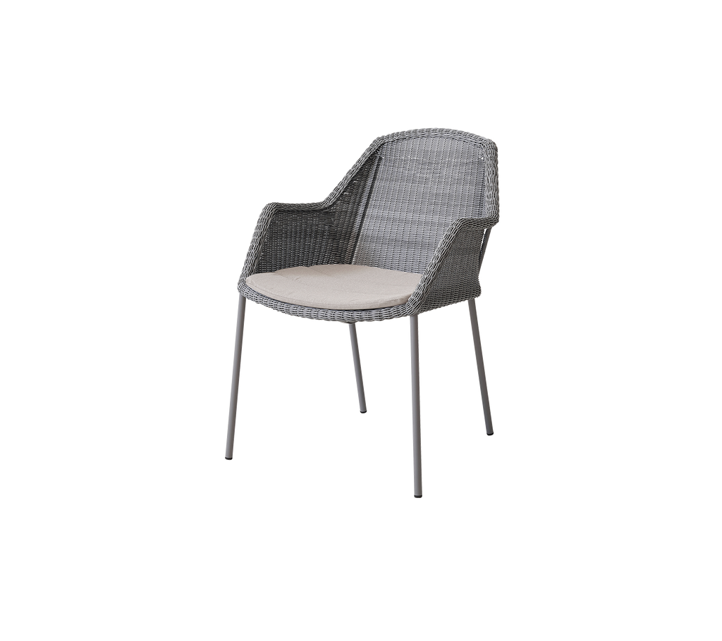 Silla tejida gris con reposabrazos, que presenta un cojín claro en un diseño minimalista, adecuada para uso exterior o interior.