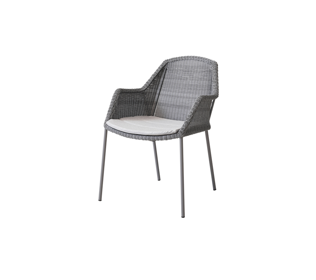 Silla tejida gris con un cómodo cojín blanco, perfecta para añadir un toque moderno a cualquier espacio.