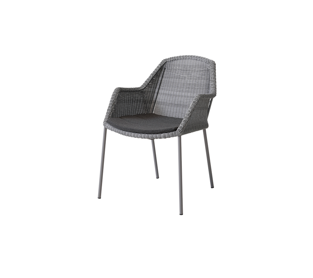 Silla tejida con estilo, con un asiento cómodo y reposabrazos, que presenta un diseño elegante y patas resistentes, perfecta para espacios modernos.