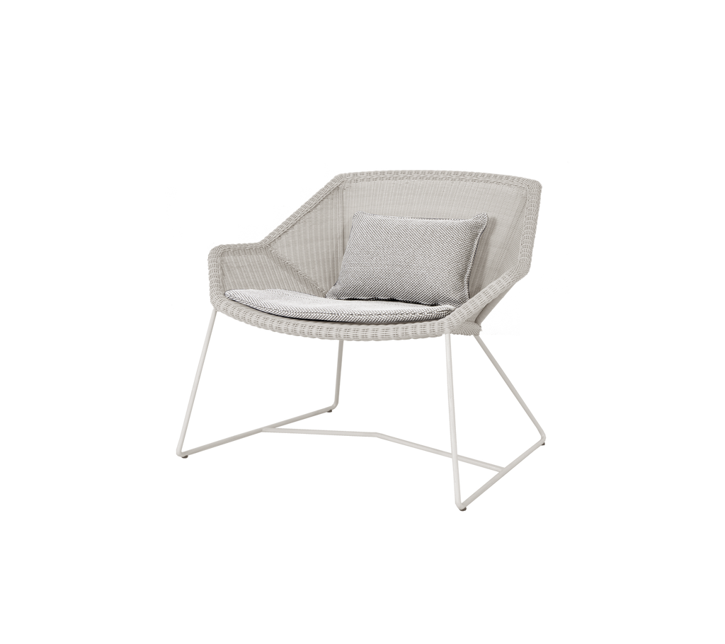 Silla gris clara con un cojín a juego en un diseño moderno.