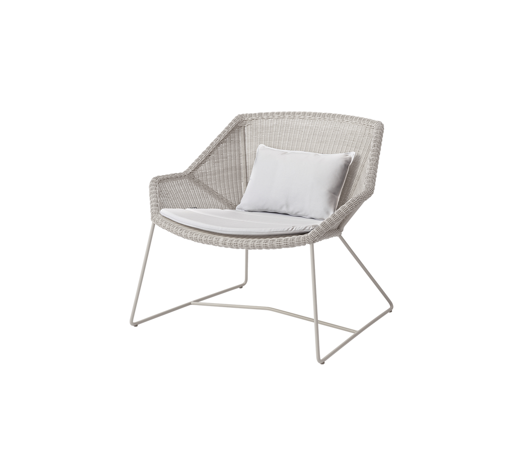 Silla blanca moderna con un cojín blanco en un entorno de salón.