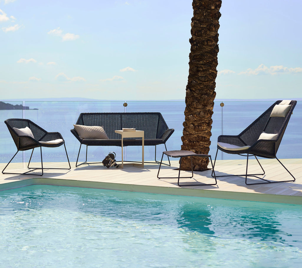 Asientos modernos en el salón con sillas negras y un loveseat junto a una piscina.