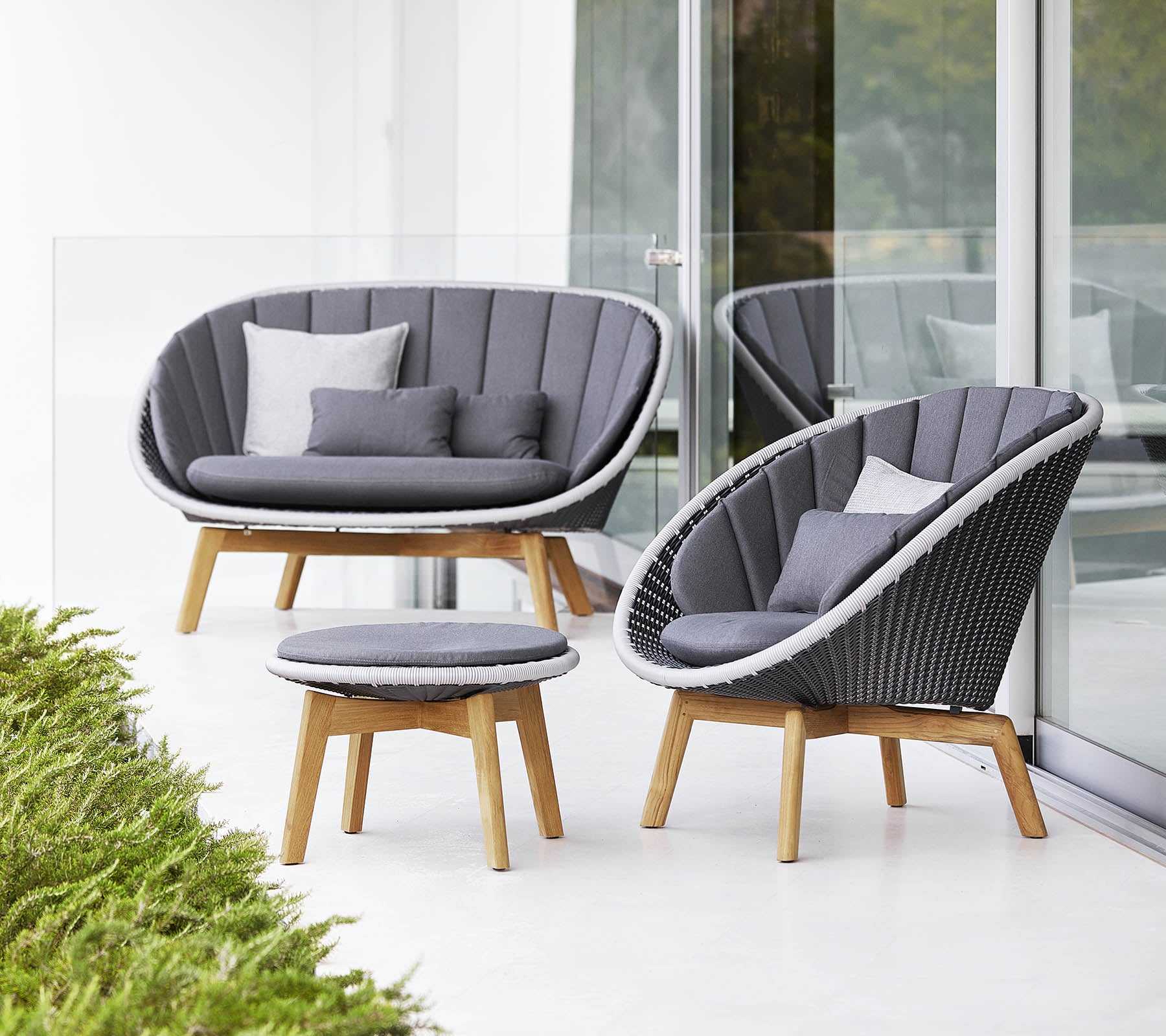 Juego de asientos elegante que incluye un sofá curvado, una silla y una mesa de café redonda, todo con un diseño moderno y suaves cojines grises.