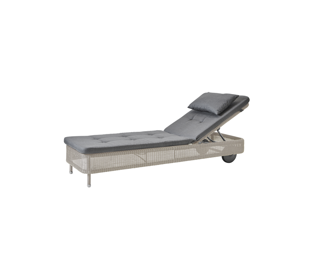 Tumbona moderna gris con un cojín color arena.