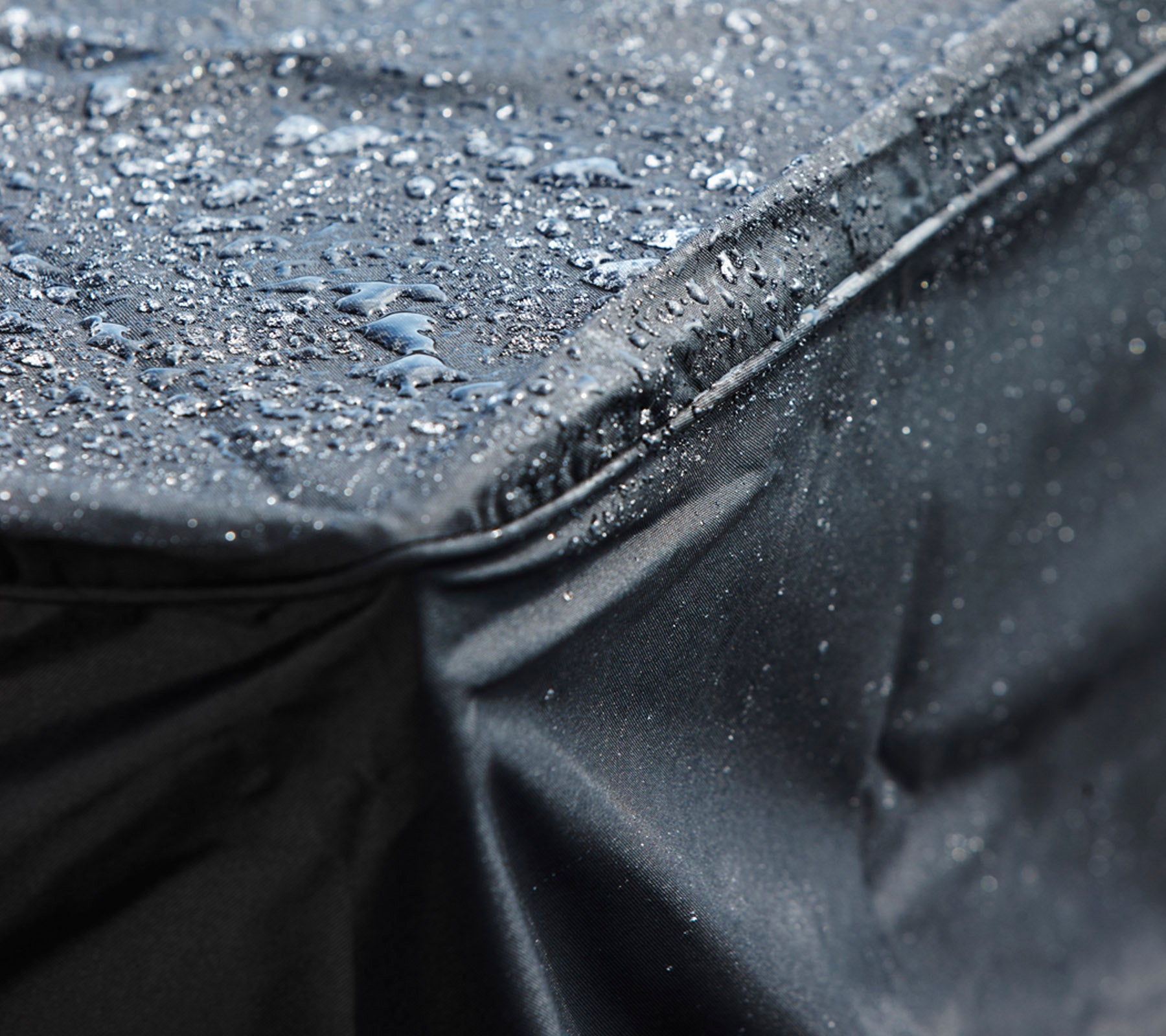 Primer plano de una funda negra impermeable con gotas de agua en su superficie, mostrando su diseño protector.
