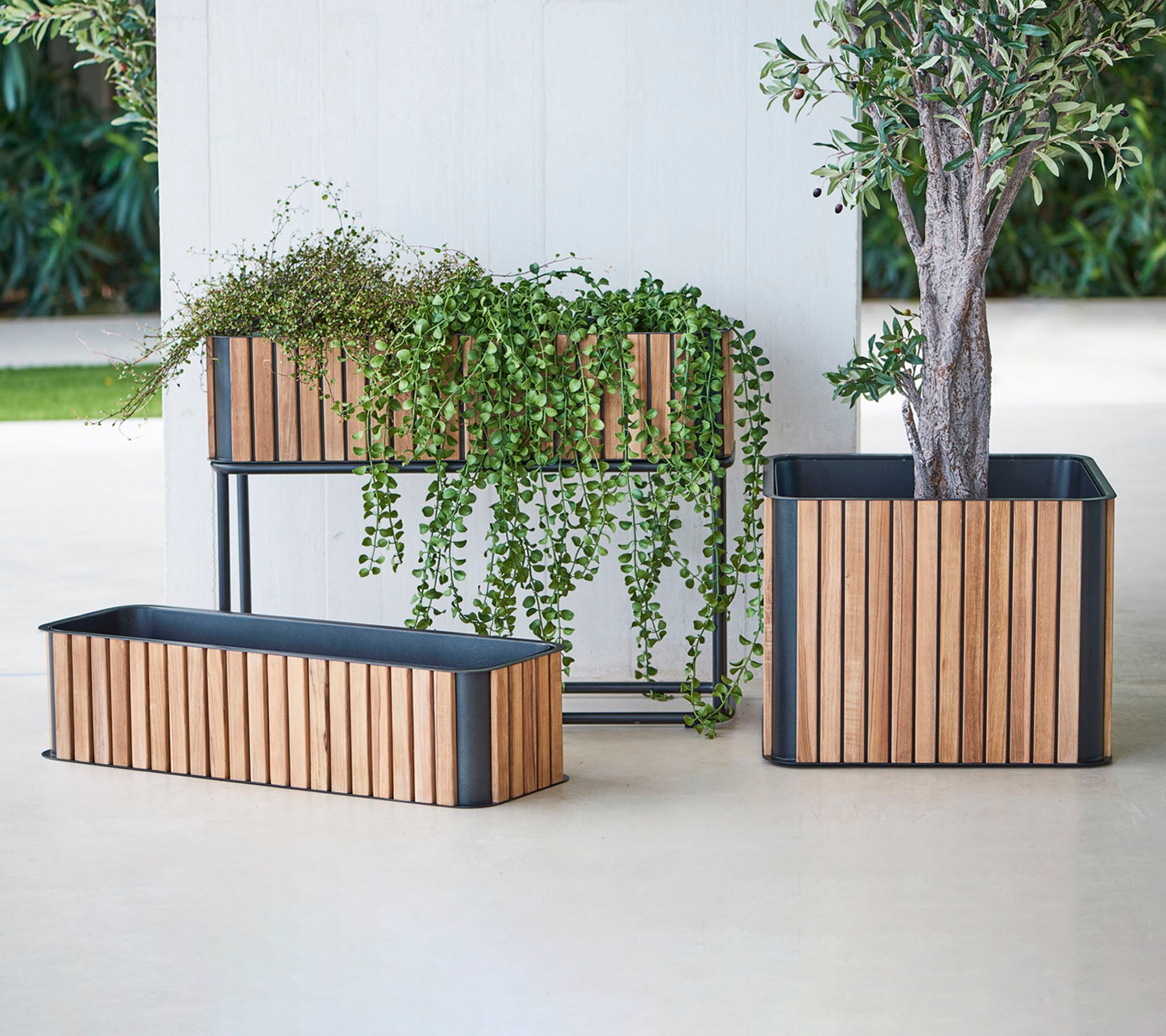 Tres macetas elegantes con listones de madera y bases de metal, que exhiben una vegetación exuberante y añaden un toque de elegancia a cualquier espacio.