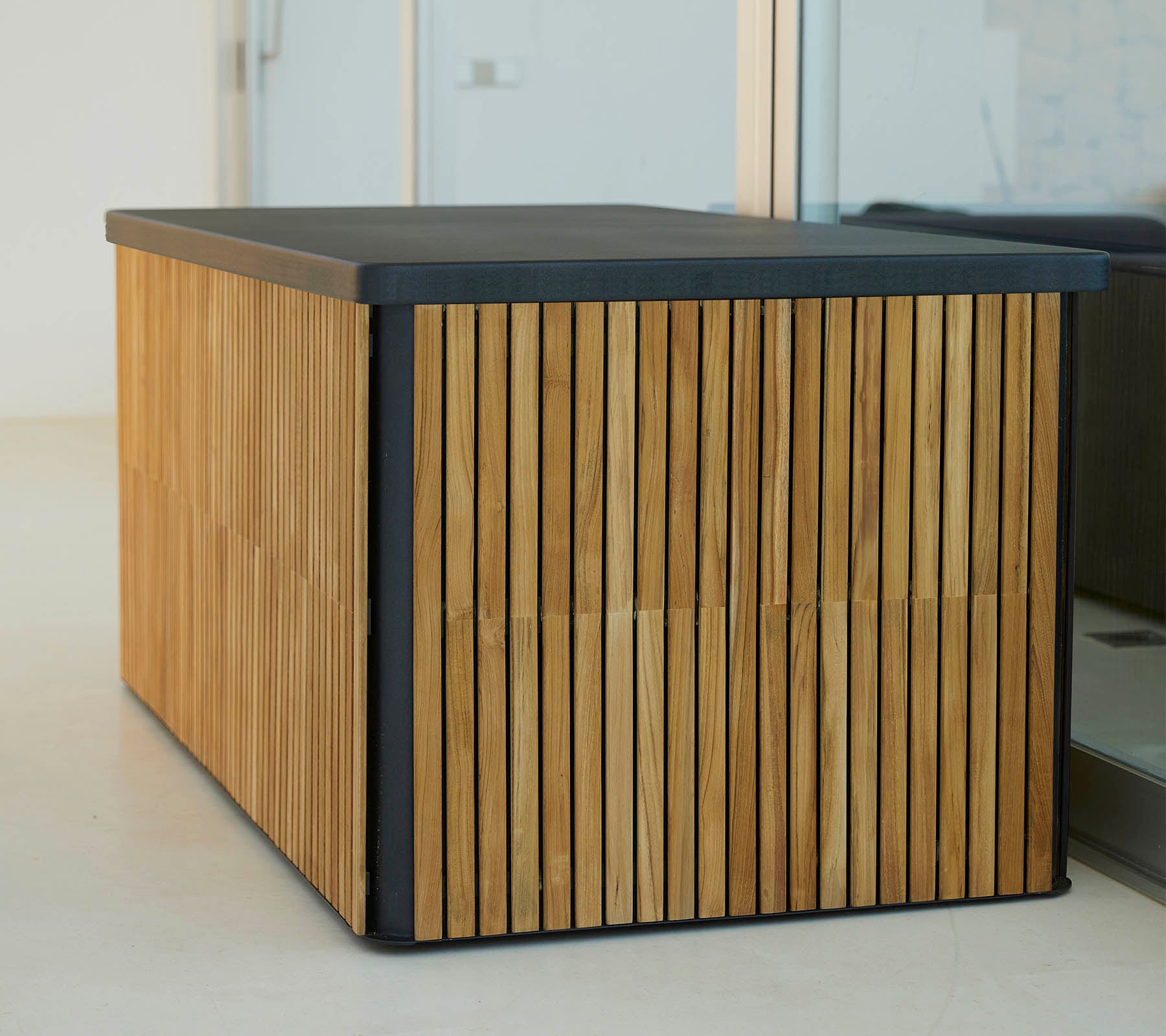 Una mesa de madera moderna con listones verticales a los lados y una parte superior oscura y elegante, que ofrece un diseño estiloso y funcional.