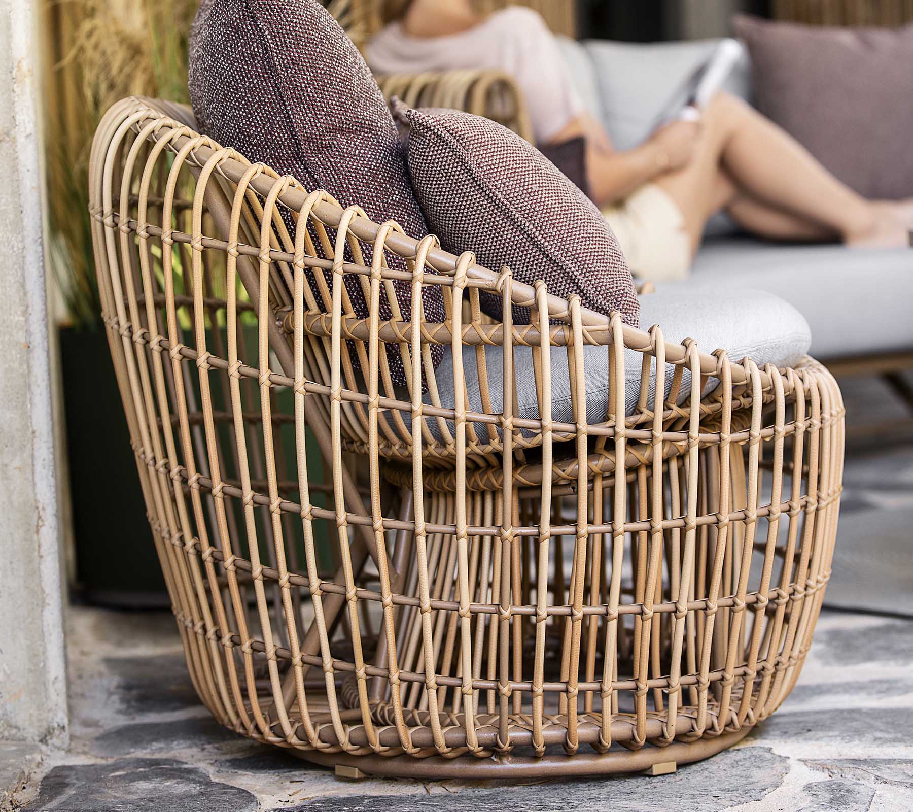 Una silla tejida y elegante con un diseño abierto, que cuenta con dos cojines suaves para mayor comodidad. Perfecta para un asiento relajado.