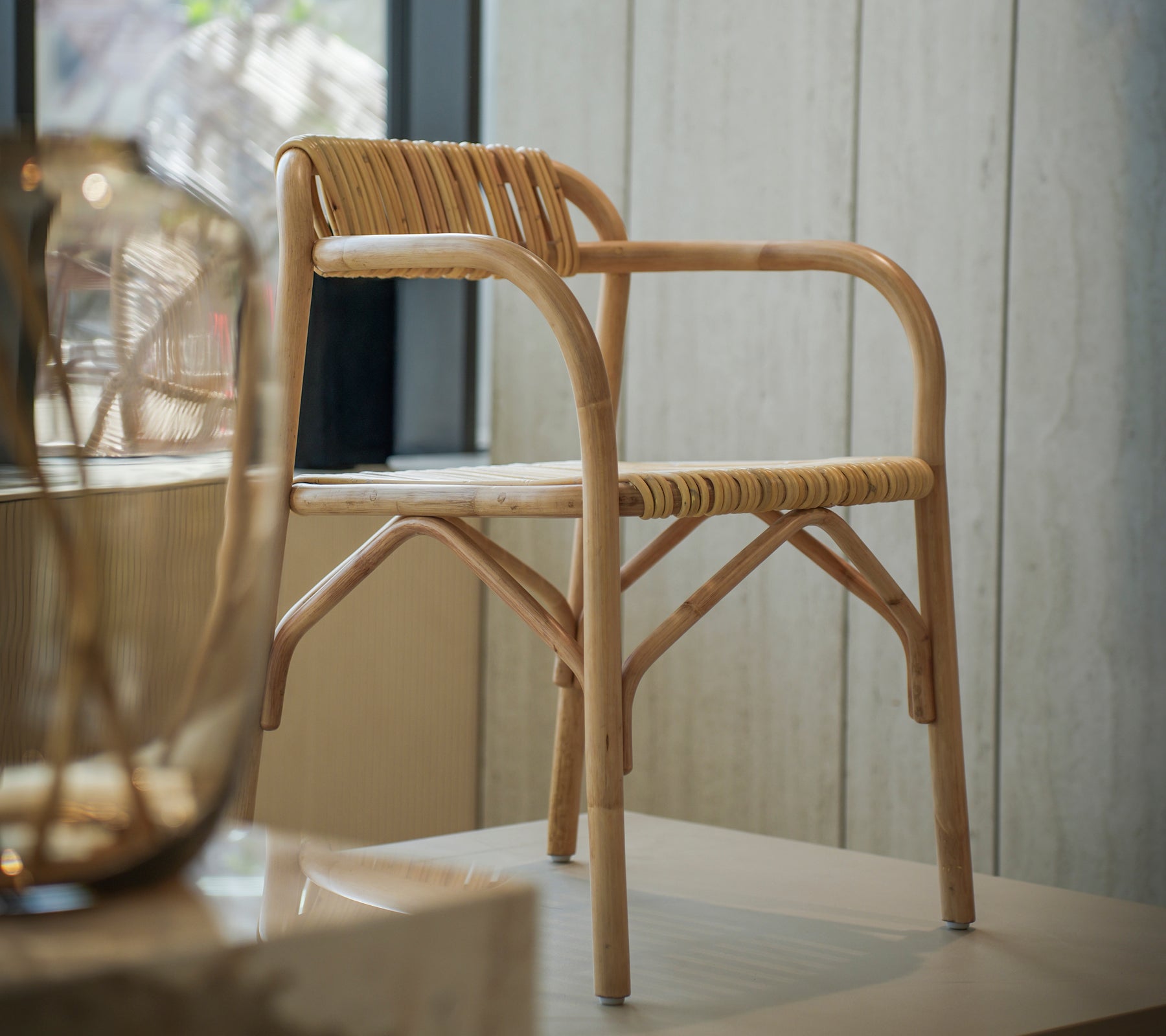Silla de bambú moderna con un asiento tejido en un espacio interior brillante.