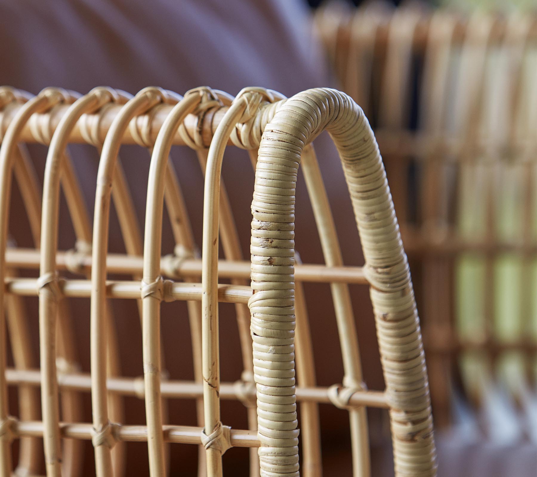 Primer plano de una silla de ratán trenzado, que presenta líneas curvas y un acabado natural, destacando su artesanía y diseño.
