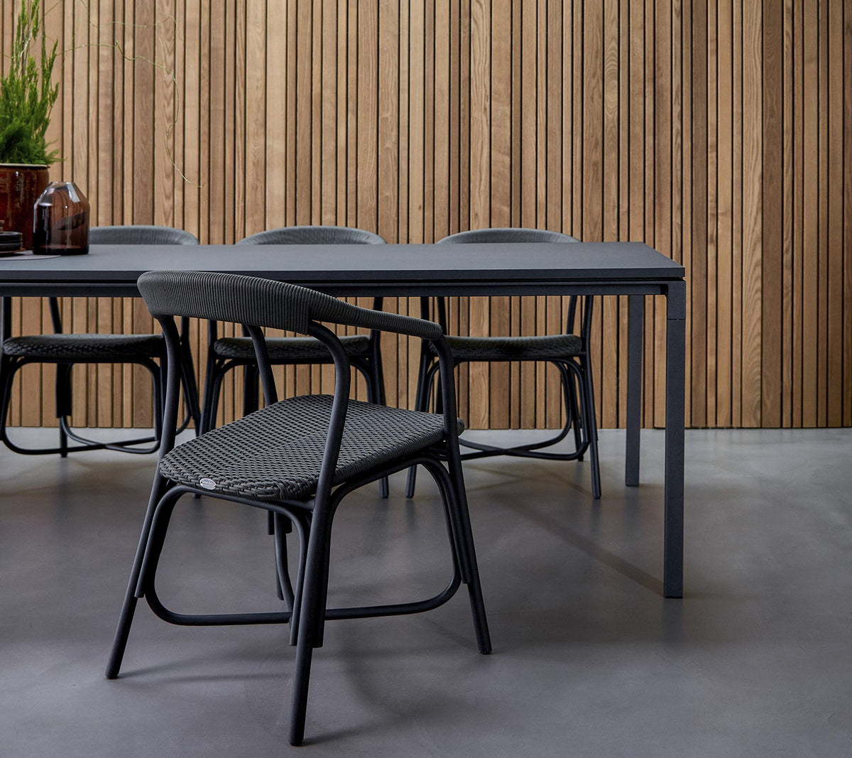 Un comedor moderno con una mesa elegante rodeada de sillas de diseño, contra un fondo de madera texturizada.