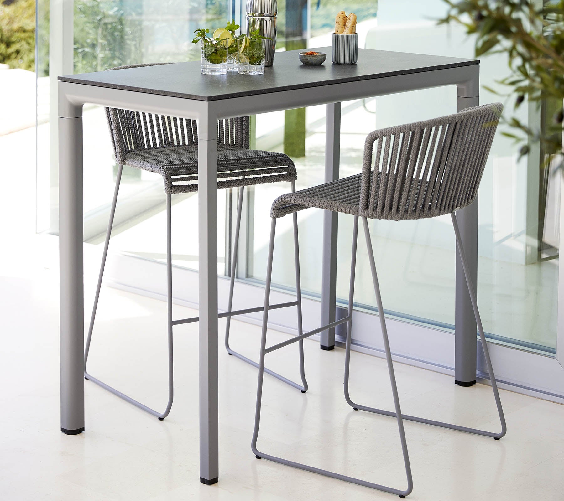 Una mesa moderna con una superficie lisa acompañada de dos elegantes sillas de respaldo alto, ideal para comidas informales o reuniones.