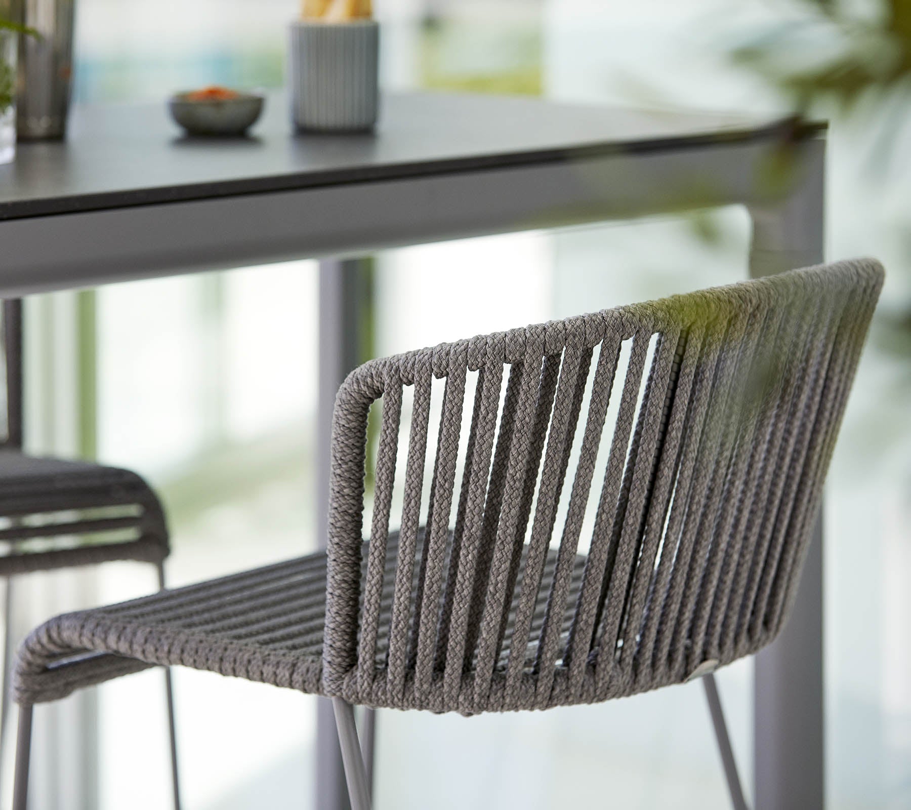 Silla gris elegante con un diseño elegante, con rayas verticales y una estética moderna, colocada junto a una mesa minimalista.