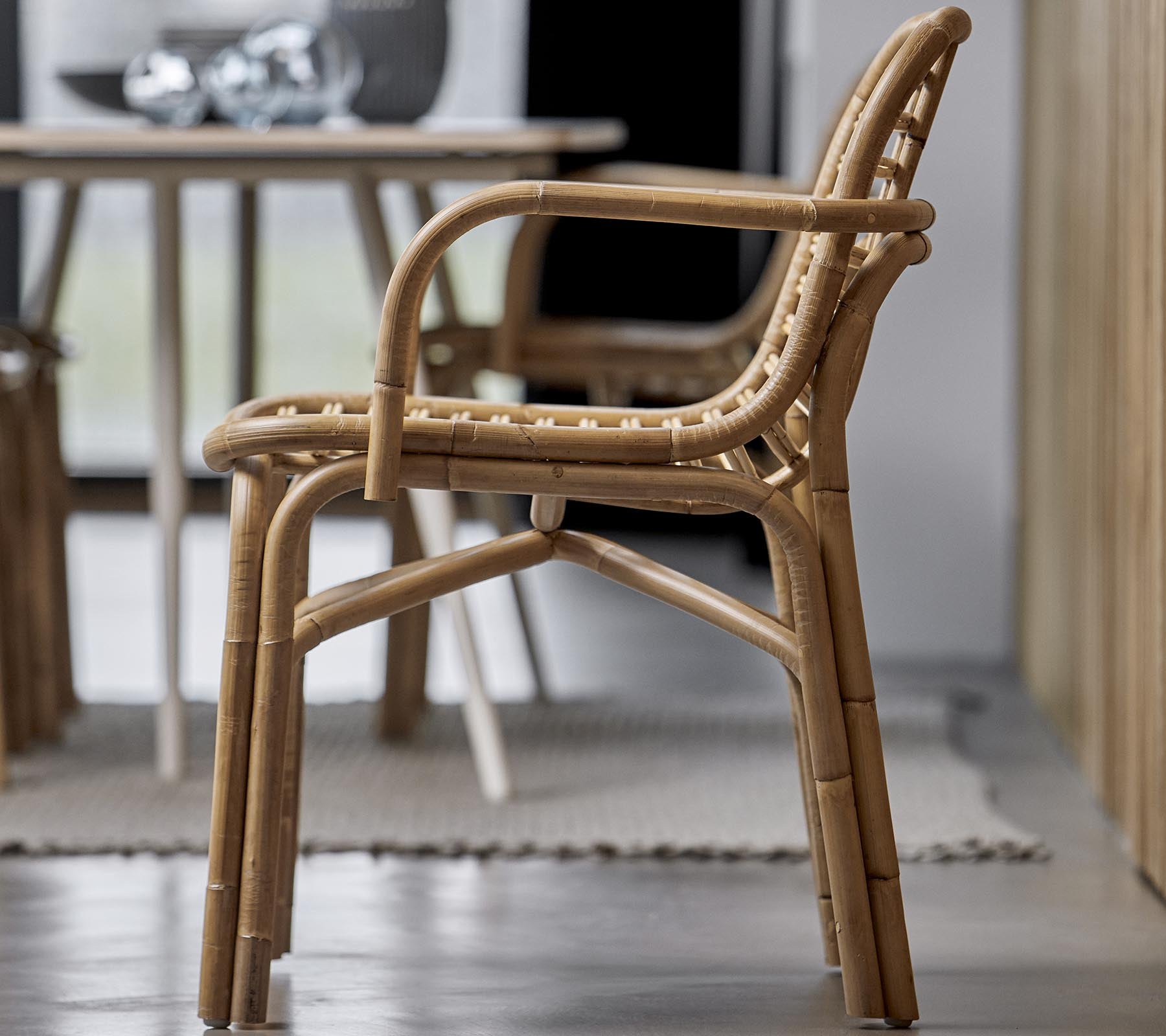 Una silla elegante hecha de materiales naturales, con un diseño trenzado y reposabrazos, adecuada para diversos entornos interiores.