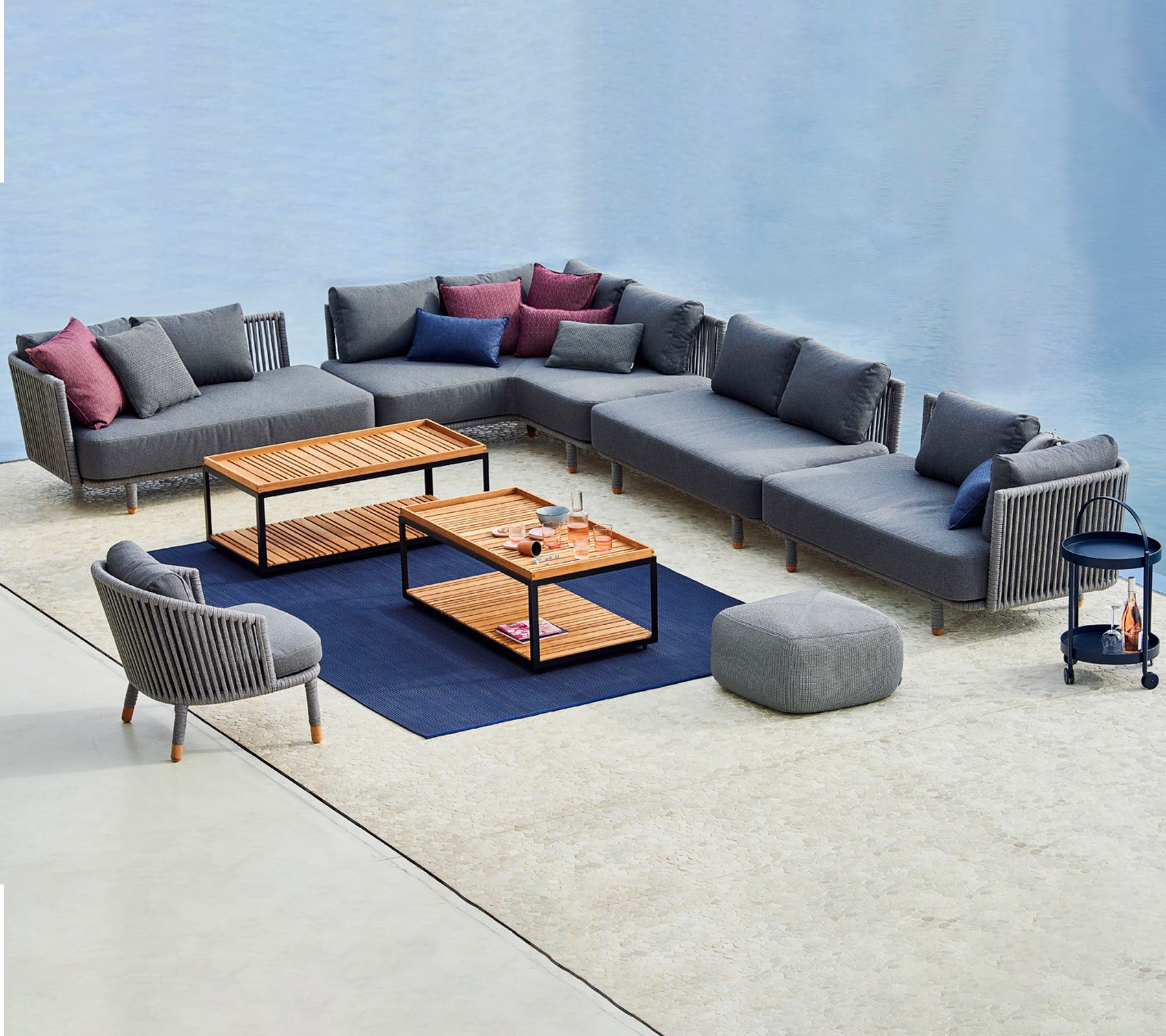 Arreglo de asientos contemporáneo que cuenta con un sofá modular gris con cojines coloridos, mesas de café y una silla de acento a juego.