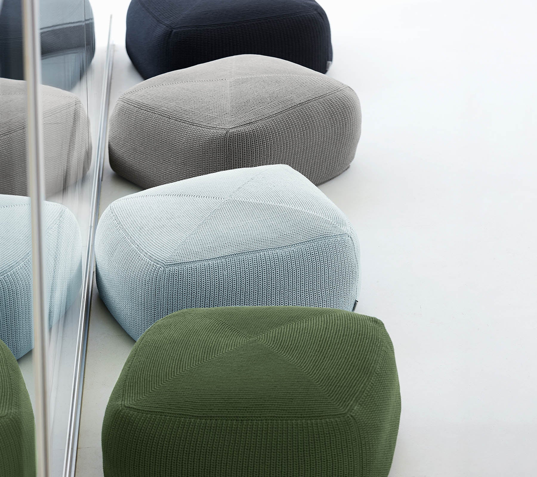 Una colección de poufs coloridos y texturizados en varias tonalidades, organizados juntos, que reflejan un diseño elegante y moderno.