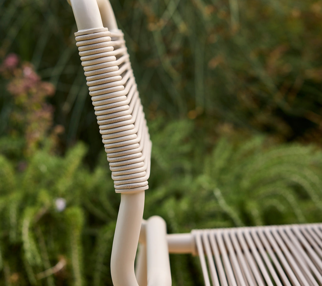 Silla beige parcialmente visible con un fondo verde borroso.