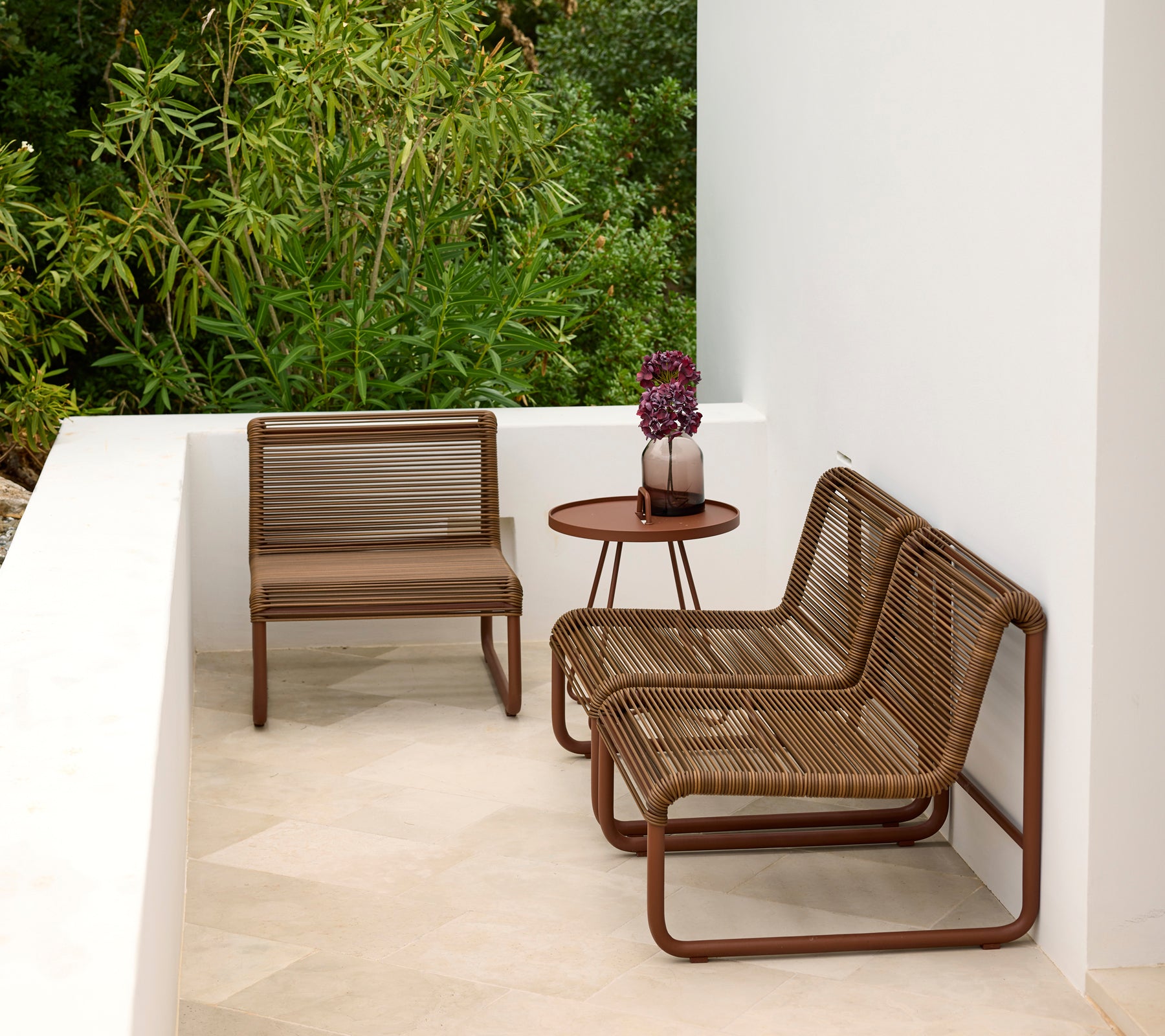 Zona de lounge exterior moderna con sillas marrones y una mesa redonda.