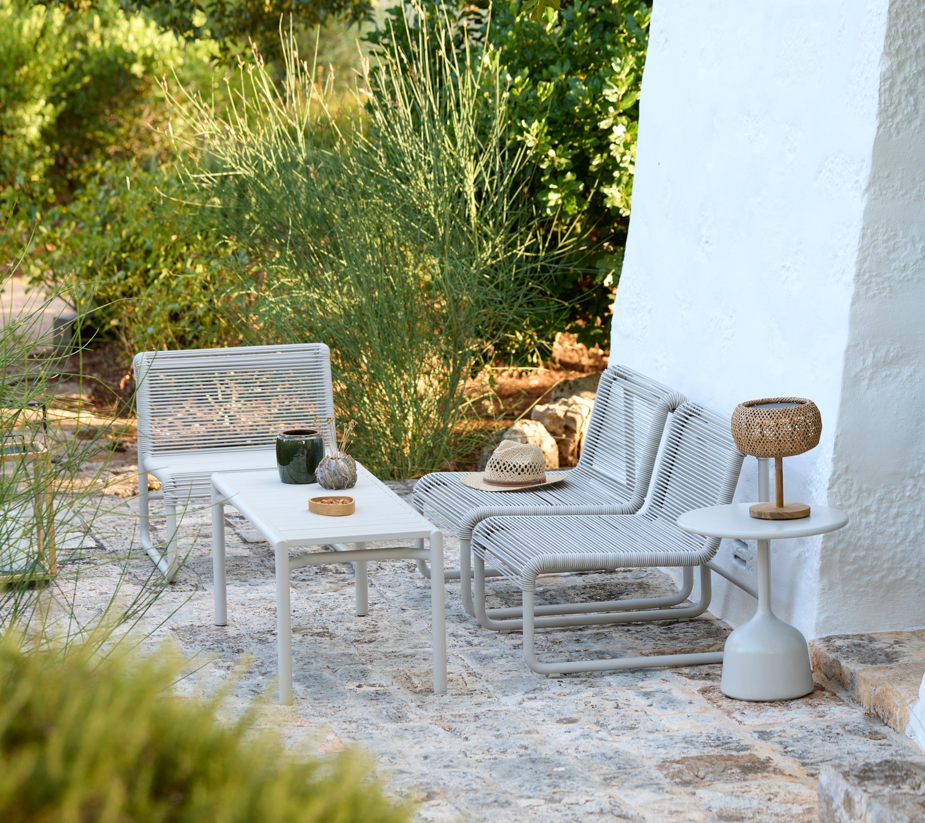 Sillas de lounge grises modernas y mesas blancas en un entorno exterior minimalista.