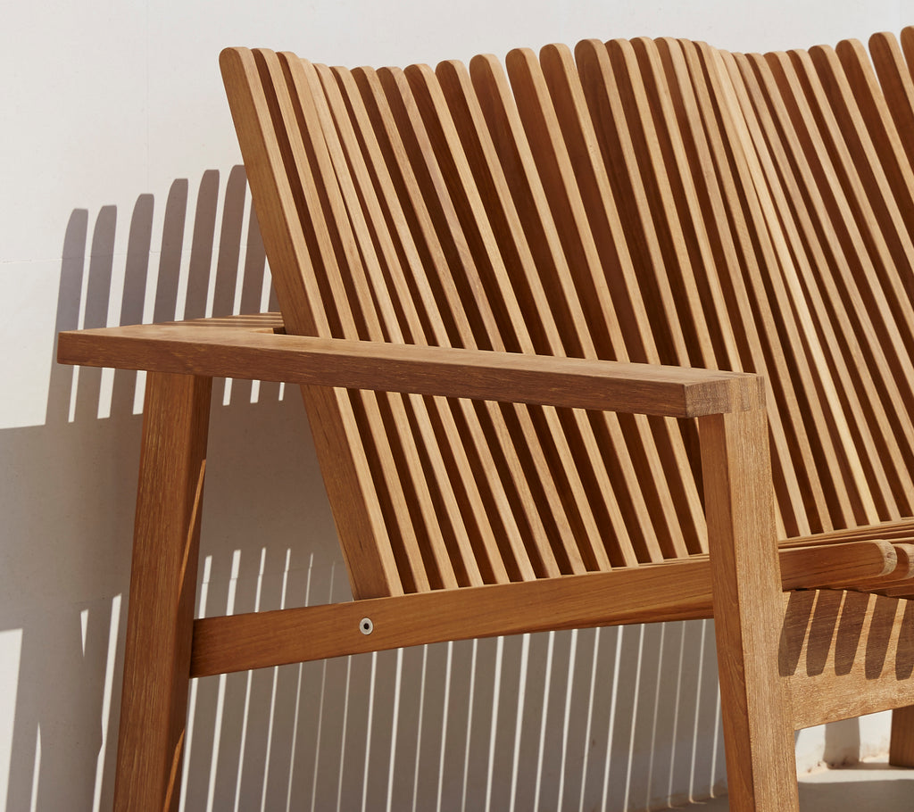Vista lateral de un sofá estiloso de 2 plazas con respaldo de listones y brazos de madera, que muestra un diseño moderno.