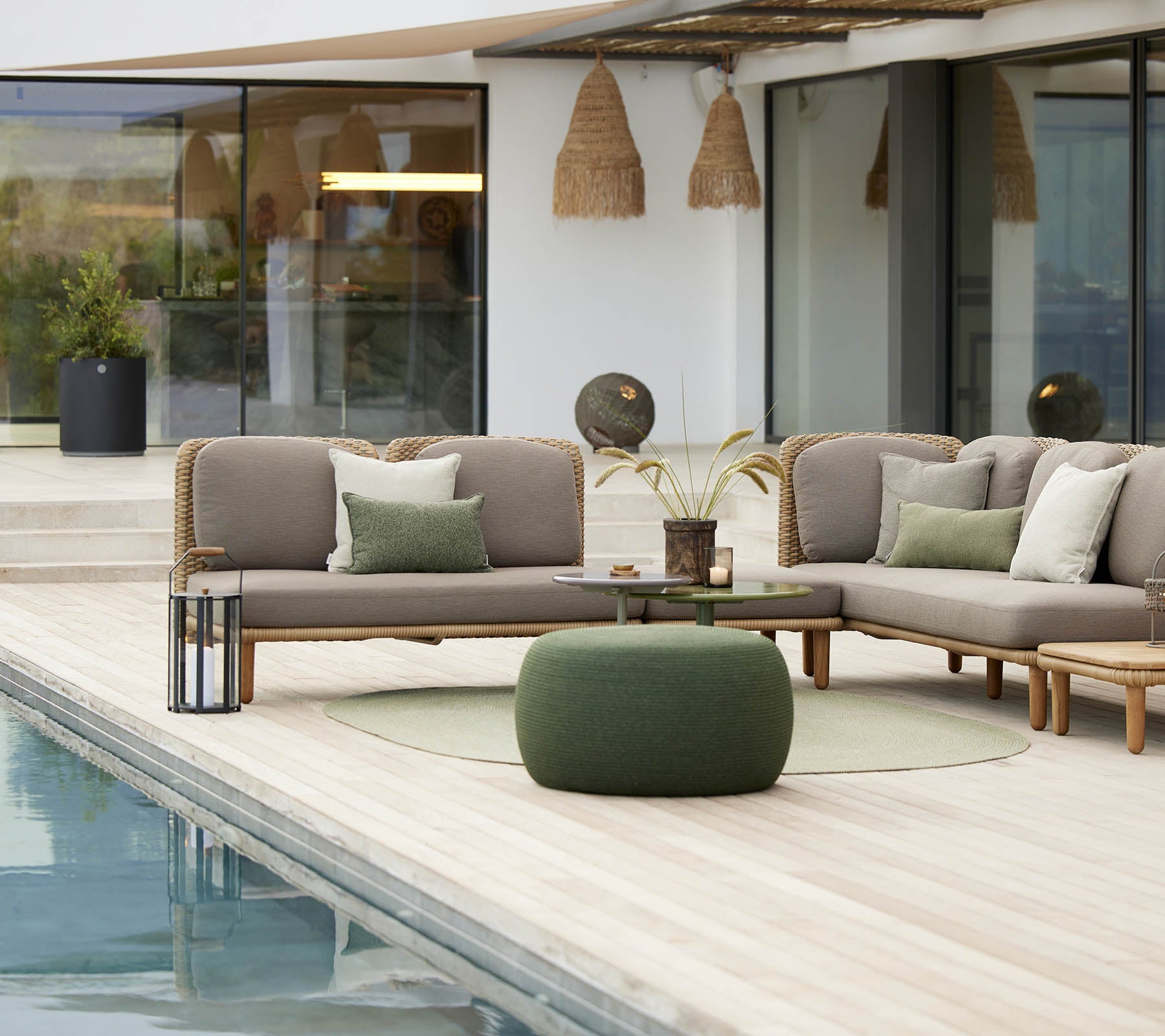 Área de asientos elegante con un acogedor reposapiés circular y un diseño en arco, complementado con cojines decorativos y vegetación.