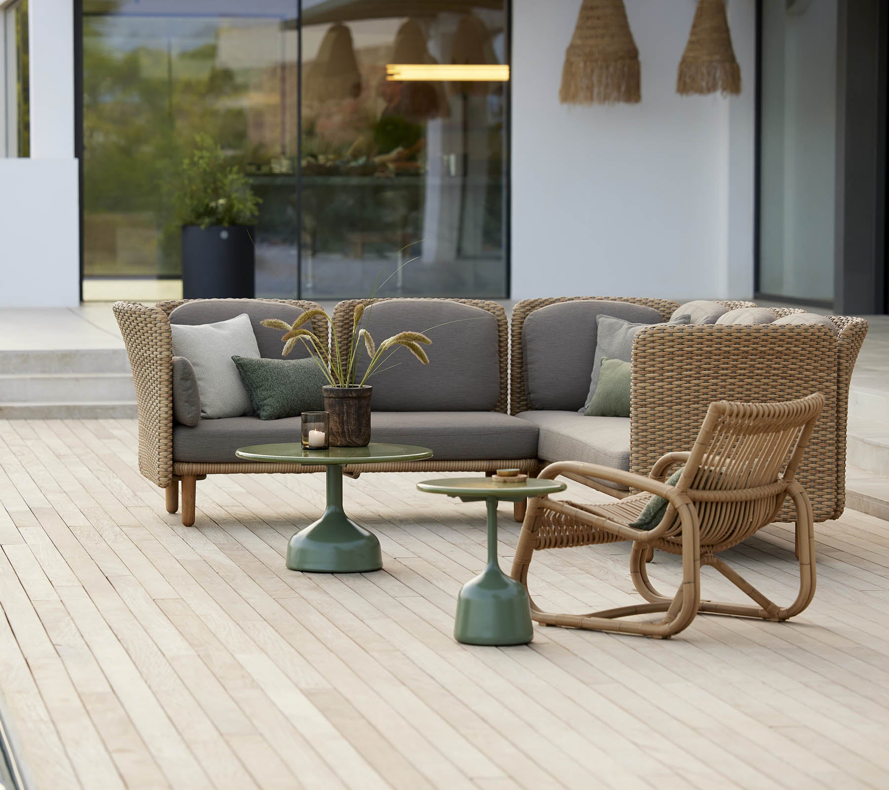 Área de estar elegante con una silla lounge curva y una mesa con una base verde, complementada con cojines suaves y elementos decorativos.