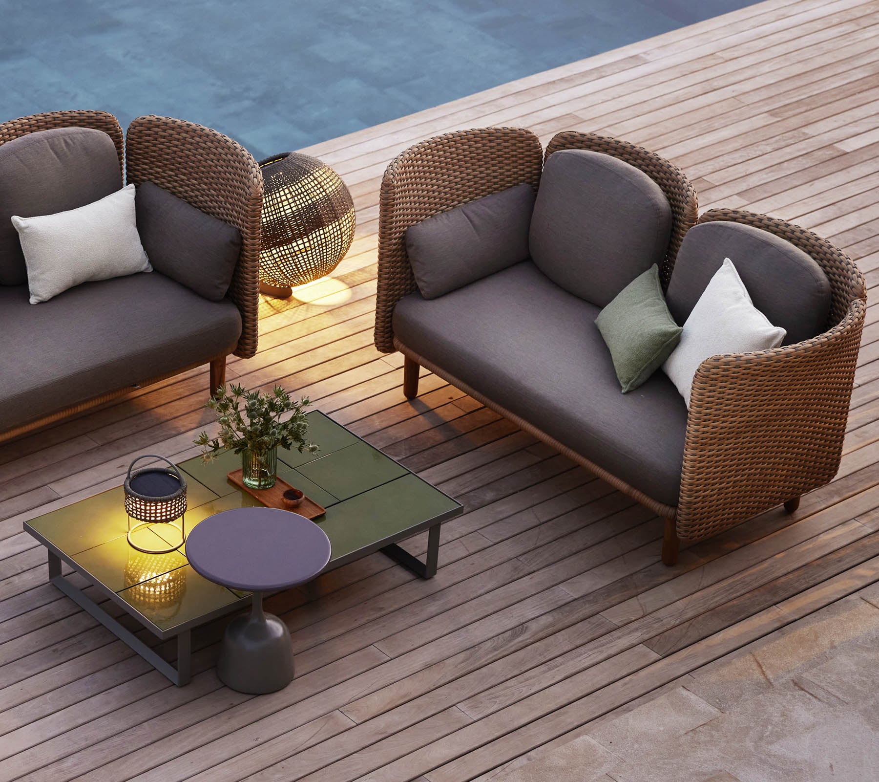 Una acogedora zona de estar con dos sofás de lounge curvados, una mesa baja, cojines decorativos y una iluminación ambiental.
