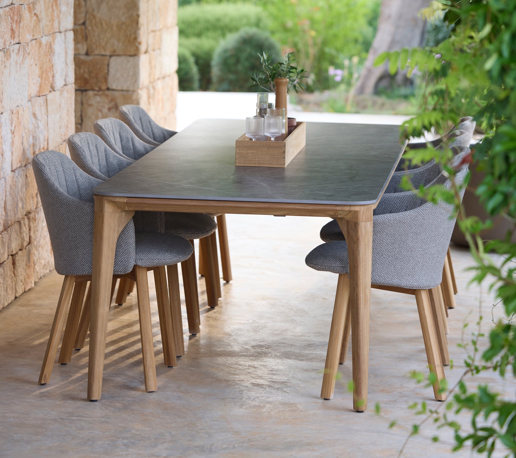 Juego de mesa de comedor moderno con sillas grises en un entorno al aire libre natural.