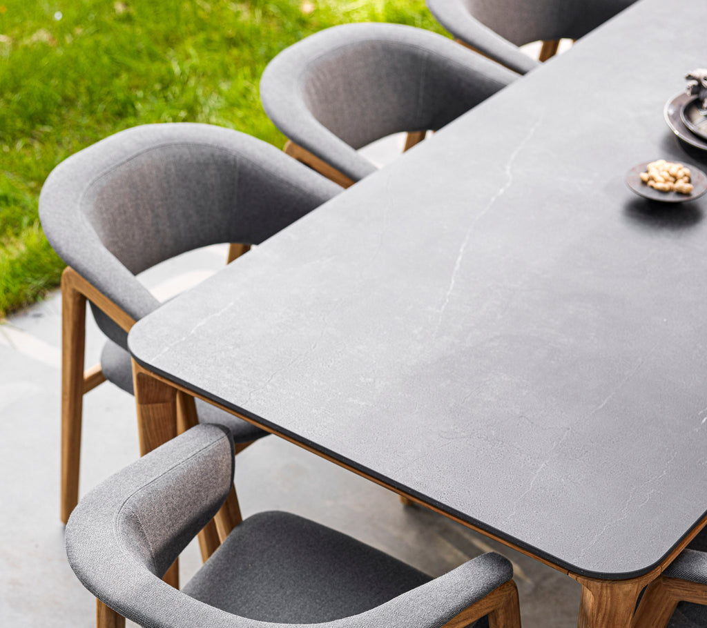 Mesa de comedor elegante con una superficie lisa, rodeada de cómodas sillas Luna con tapicería suave y patas de madera.