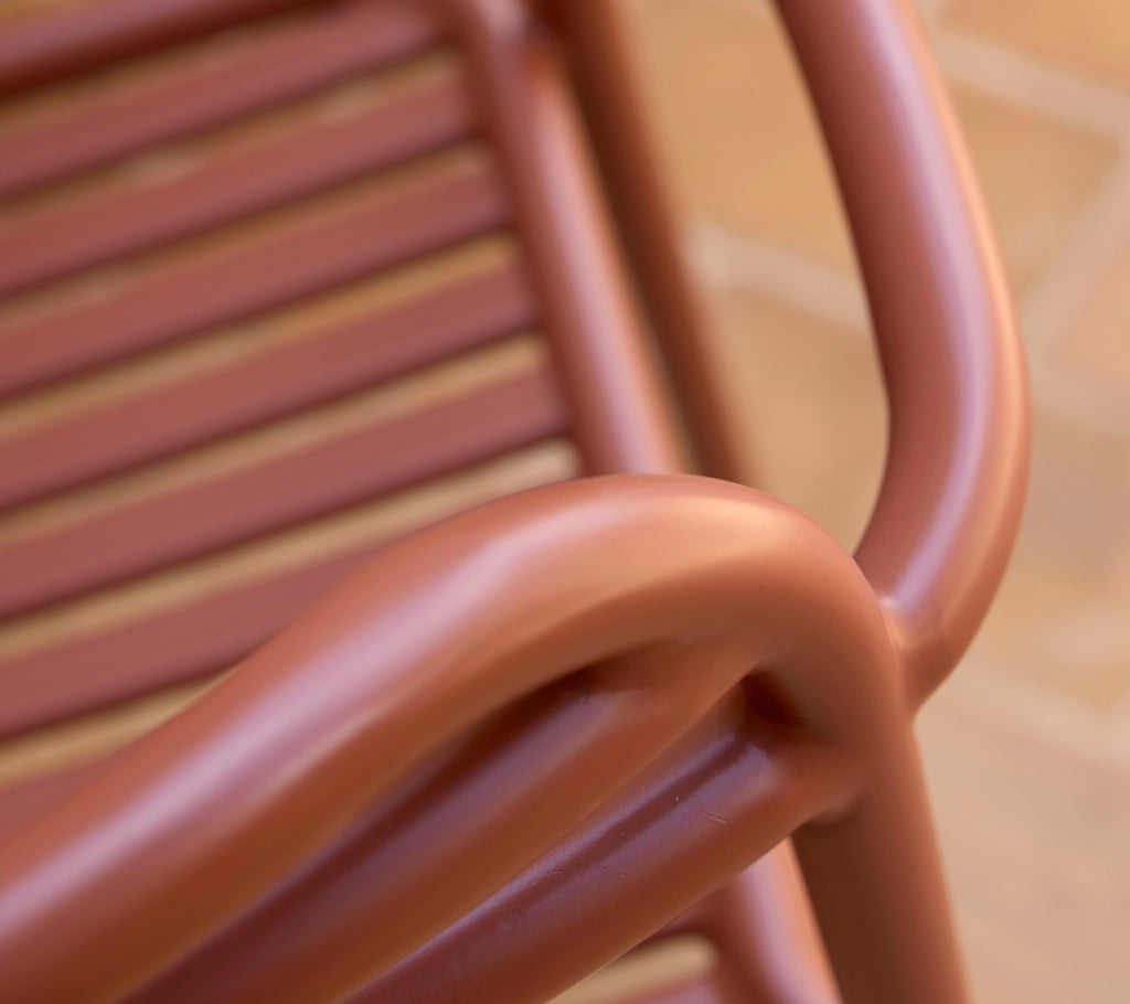 Primer plano de una silla Bliss en un tono rojo desértico, mostrando sus suaves curvas y diseño de listones.
